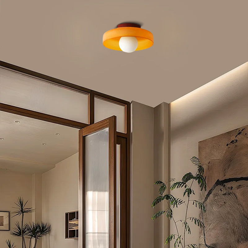 modern round ceiling light in dining area, orange metal glass